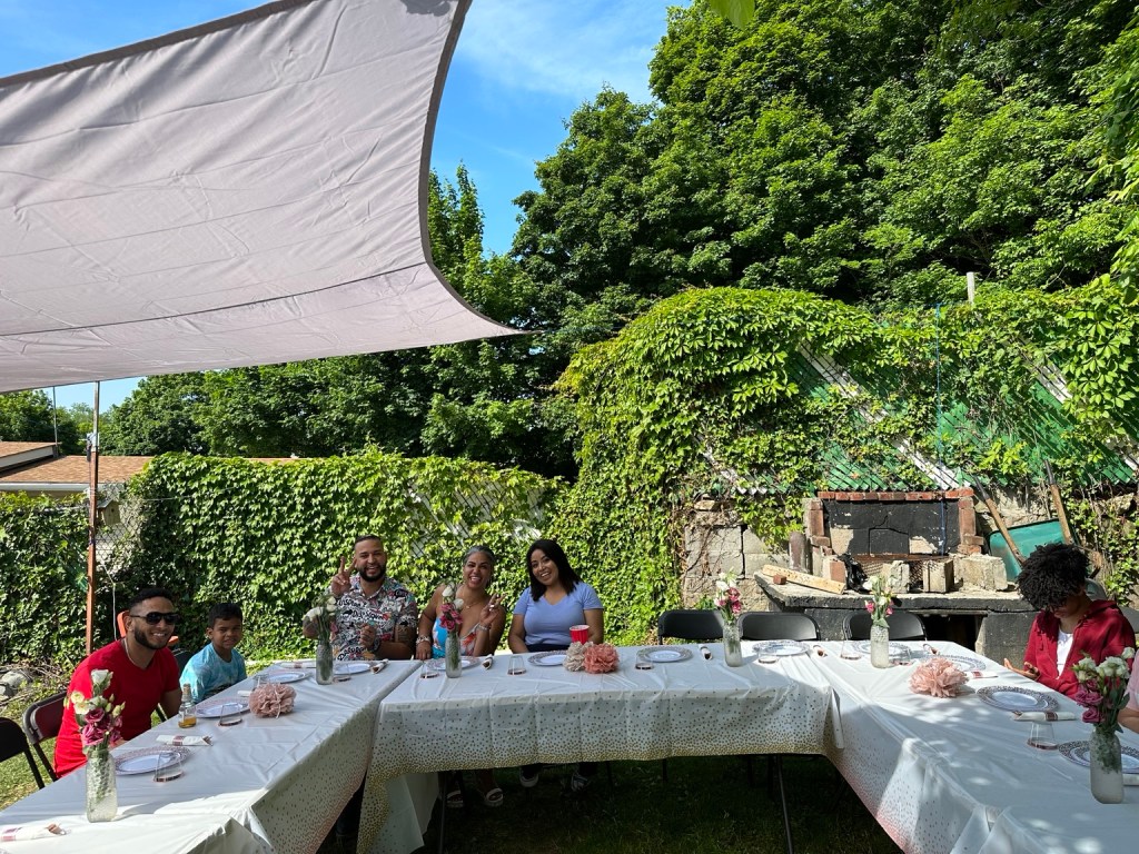 Guests seated around white-clothed tables in a backyard at a real hibachi party